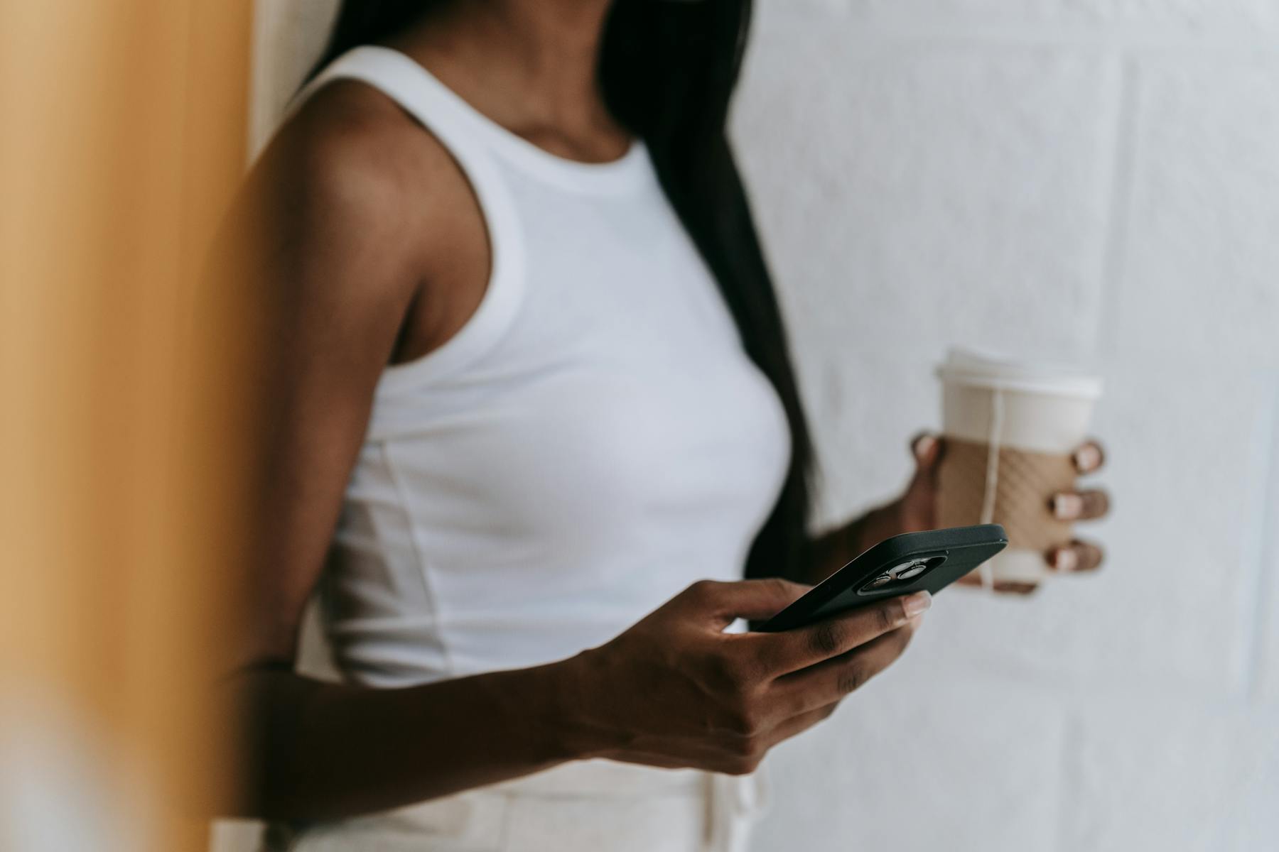 Persona con el móvil en la mano tomando un café